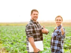 Due agricoltori sorridenti in un campo, dopo una consulenza agronomica di successo.