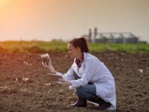 Una ricercatrice effettua analisi del terreno durante una consulenza agronomica in campo.